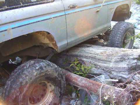 1984 Ford Bronco II - This Ford Bronco is navigating a rough, off-road terrain with large logs and rocks.