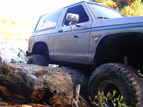 1984 Ford Bronco II - This 1984 Ford Bronco II is shown navigating a challenging off-road course, climbing over large fallen trees.