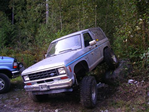 1984 Ford Bronco II - A silver Ford Bronco II is parked on a rocky incline next to a blue pickup truck.