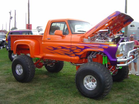 1978 Ford Bronco - Customized pickup truck with flames and lifted suspension is displayed outdoors.