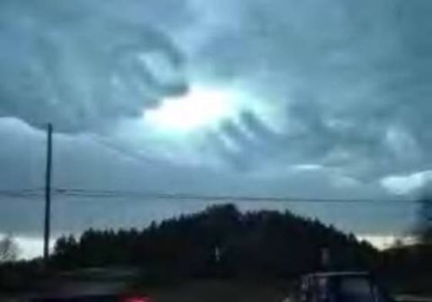 1994 Ford Crown Victoria - The sun shines through dramatic storm clouds, casting a glow over a dark landscape.