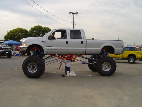 1978 Ford Bronco - A heavily modified silver pickup truck with extreme lift and large tires is parked outdoors.