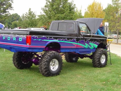 1978 Ford Bronco - This heavily modified Ford pickup truck features a custom paint job with purple and teal graphics and oversized off-road tires.