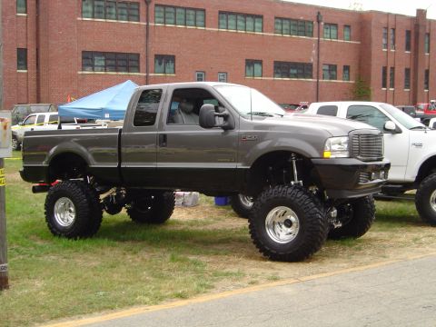 1978 Ford Bronco - Gray Ford F-250 Super Duty pickup truck with custom lift kit and large tires parked outdoors.