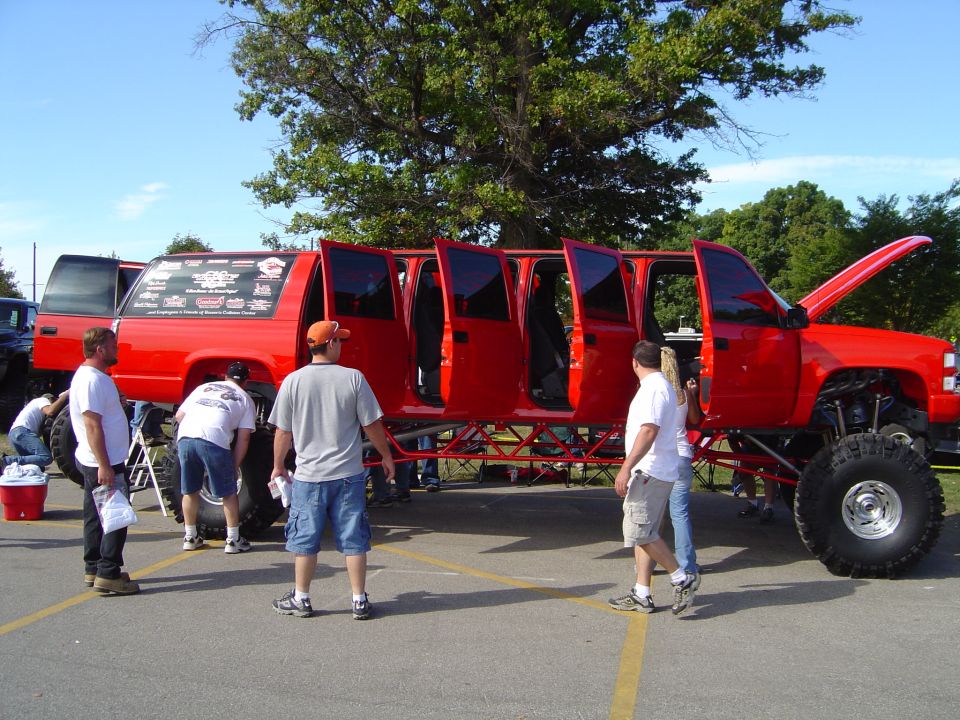 Red stretched SUV limousine with seven doors on each side, lifted on large tires