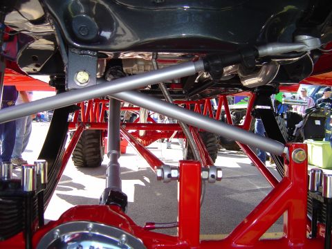 1978 Ford Bronco - The underside of a heavily modified vehicle reveals custom suspension components and large off-road tires.