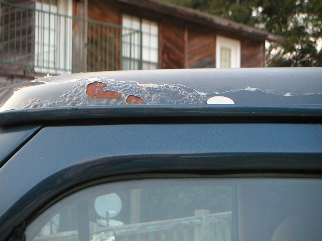 rusted paint on dark green vehicle roof