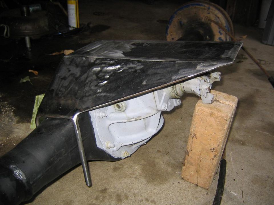 Differential housing with a black metal skid plate, supported by a wooden block