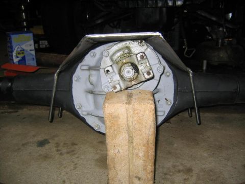 1978 Ford Bronco - Rear differential assembly shown with a protective metal cover and supported by a wooden block.