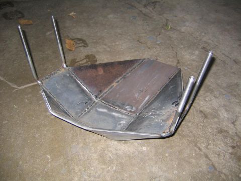 1978 Ford Bronco - A fabricated skid plate made of welded metal pieces sits on a concrete floor.