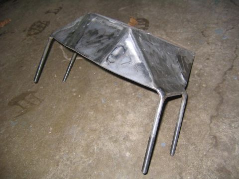 1978 Ford Bronco - A metal skid plate with four legs rests on a concrete surface.