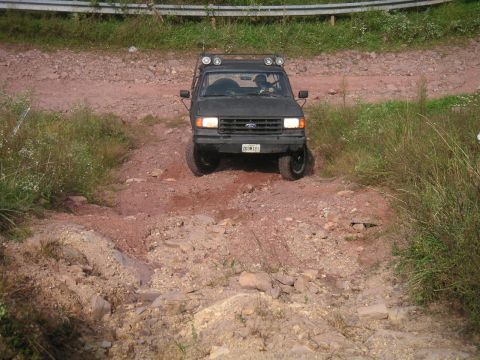 1994 Ford Bronco - This 1994 Ford Bronco navigates a challenging off-road course, its front grille and body style clearly identifiable.