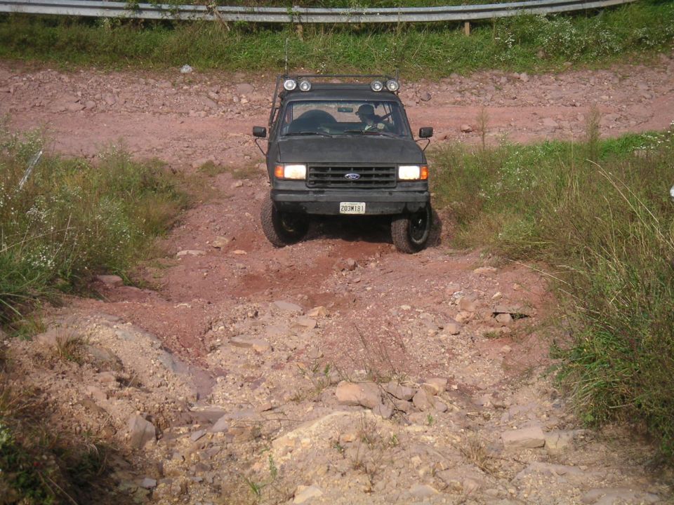 Dark 1994 Ford Bronco on a rocky trail with roof lights