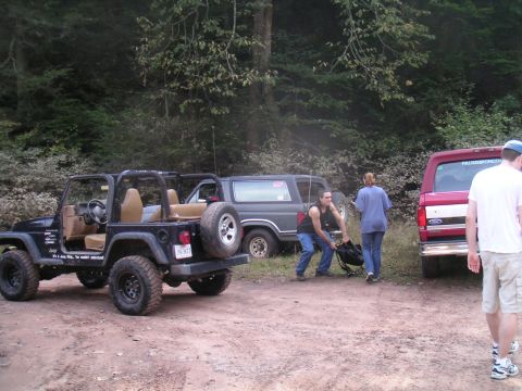 1994 Ford Bronco - Three off-road vehicles are parked on a dirt path in a wooded area.