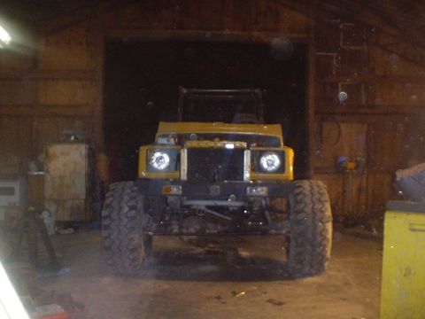 1989 Ford Bronco - Off-road vehicle with large tires sits in a dimly lit garage.