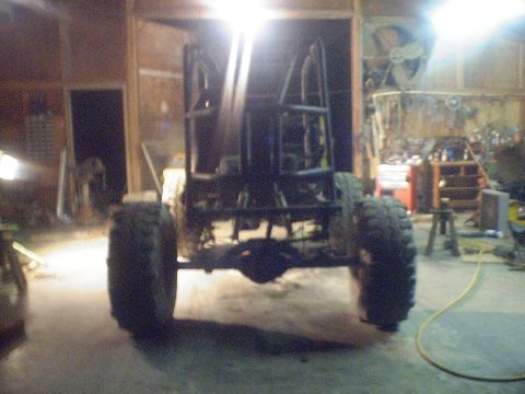 1989 Ford Bronco - Custom off-road buggy frame with large tires and roll cage, viewed from the rear.