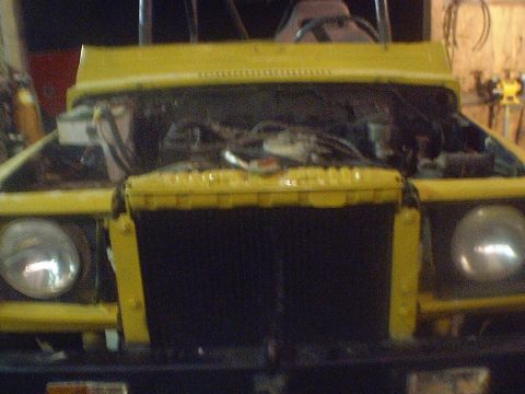 1989 Ford Bronco - The front of a yellow SUV with its hood open reveals the engine compartment and radiator.