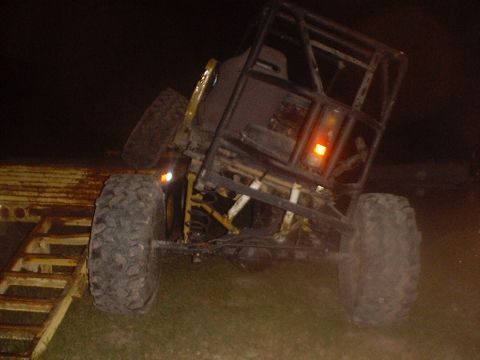 1989 Ford Bronco - Custom off-road vehicle with a prominent roll cage is being loaded onto a trailer at night.