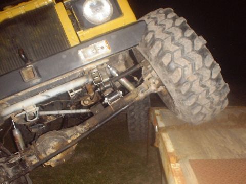 1989 Ford Bronco - Close-up of off-road vehicle's front suspension and wheel, with tire on a trailer.
