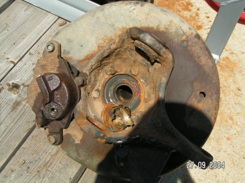 1978 Ford Bronco - This heavily rusted brake assembly shows significant wear and damage to the rotor and caliper mounting points.