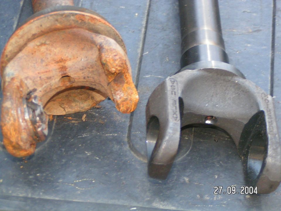 old rusty driveshaft U-joint next to a new one