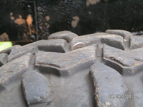 1978 Ford Bronco - A coin is lodged in the tread of a large off-road tire, with a date stamp visible in the corner.