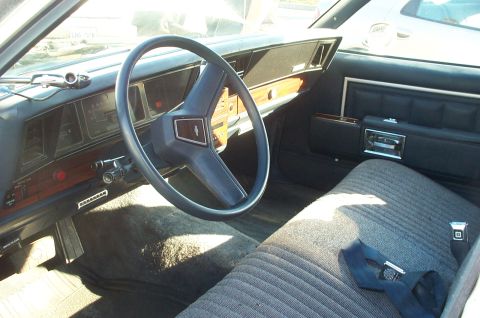 1995 Ford Crown Victoria - The interior of a car shows a dashboard with analog gauges and a large steering wheel, along with fabric-covered seats.
