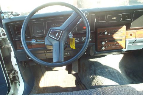 1995 Ford Crown Victoria - The dashboard and steering wheel of a car interior are visible, with a wood-grain trim and a cassette player.