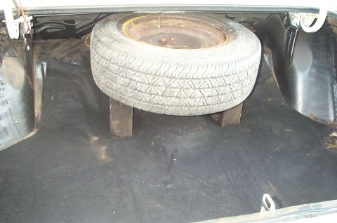 1995 Ford Crown Victoria - The trunk of a car shows a spare tire resting on wooden blocks.