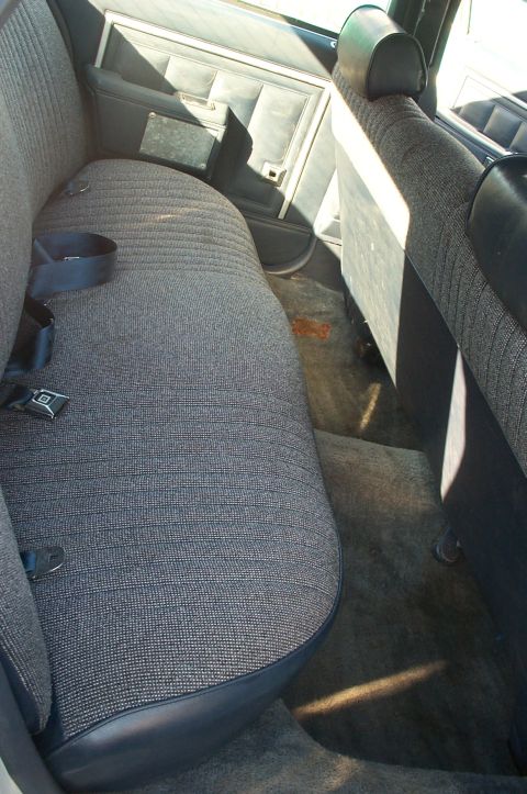 1995 Ford Crown Victoria - Interior view of a car's rear seating area with dark fabric upholstery and visible carpet stains.