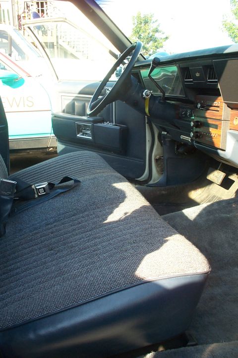 1995 Ford Crown Victoria - The interior of a car is visible, showing the seats, steering wheel, and dashboard, with another vehicle partially seen through the window.