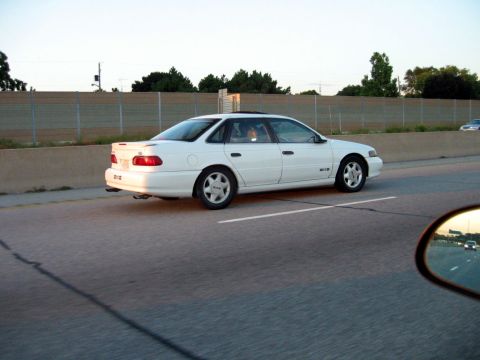 1993 Ford Taurus - A white 1993 Ford Taurus sedan is seen from the side while driving on a highway.