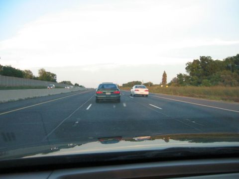 1993 Ford Taurus - A view from inside a vehicle looking at two other cars on the highway during the day.