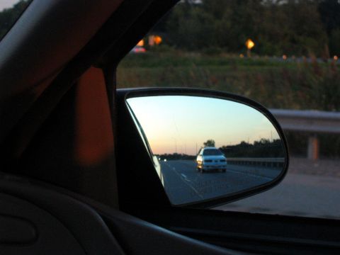 1993 Ford Taurus - A 1993 Ford Taurus is reflected in the side mirror while driving on the highway at dusk.
