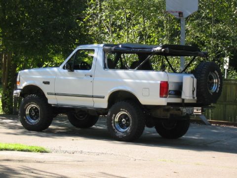 1995 Ford Bronco - White 1995 Ford Bronco with its soft top removed, seen from the rear with a spare tire carrier.