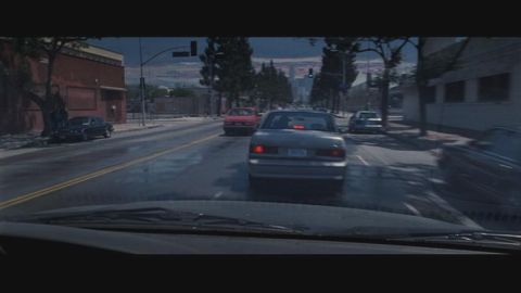1998 Ford Taurus - A silver 1998 Ford Taurus is seen from the driver's perspective on a city street, following other vehicles.