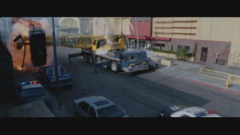 1998 Ford Taurus - A chaotic scene unfolds on a city street with a crane truck, an overturned burning car, and police presence.