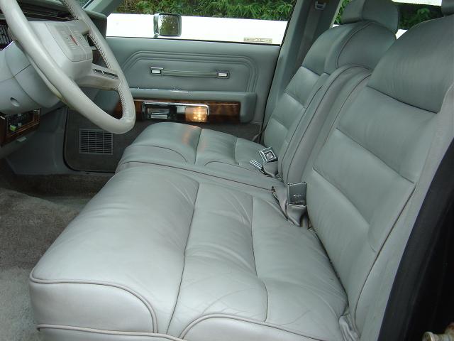 Gray leather front bench seat interior of a full-size sedan with woodgrain door trim