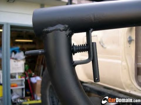 1979 Ford Bronco - A close-up view of a custom roll cage bracket with a spring-loaded pin, attached to a vehicle.