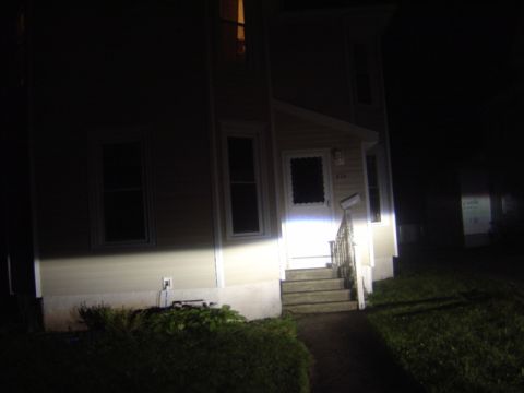1998 Ford Taurus - A house is illuminated by bright headlights at night, casting light on the front entrance and stairs.