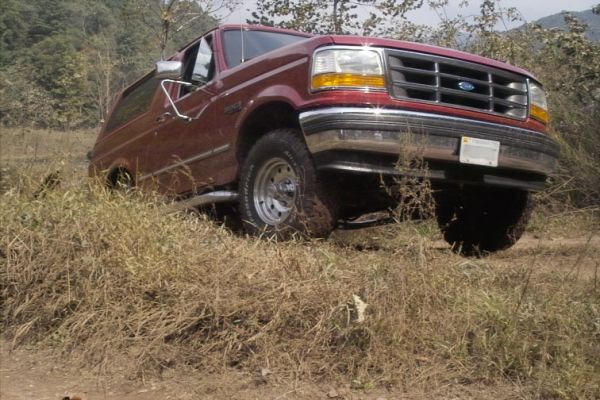 Red 1994 Ford Bronco driving off-road