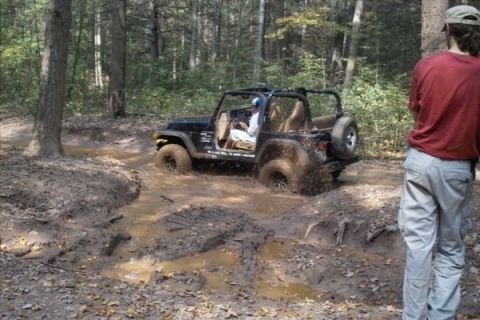 1994 Ford Bronco - Off-roading in a Jeep Wrangler, navigating a challenging muddy path.