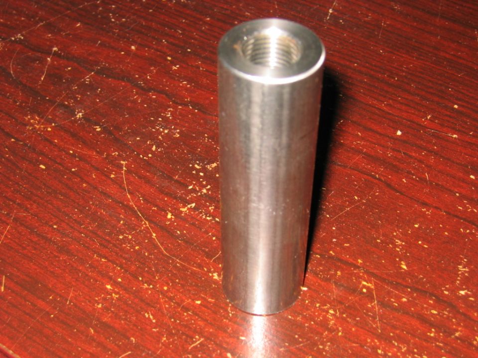 Metal threaded cylinder part on wooden surface