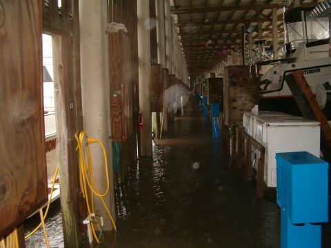 1991 Ford Bronco - A flooded marina shows boats docked alongside pilings, with water covering the ground and hoses visible.
