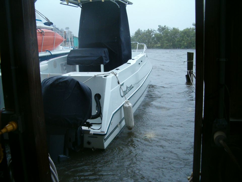 White boat with black cover on stern, docked in choppy water