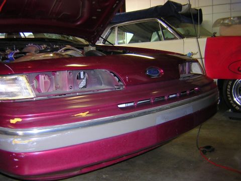 1992 Ford Crown Victoria - Front 3/4 view of a maroon/burgundy Ford sedan with the hood raised, showing a missing right headlight and exposed headlight bucket, plus a…