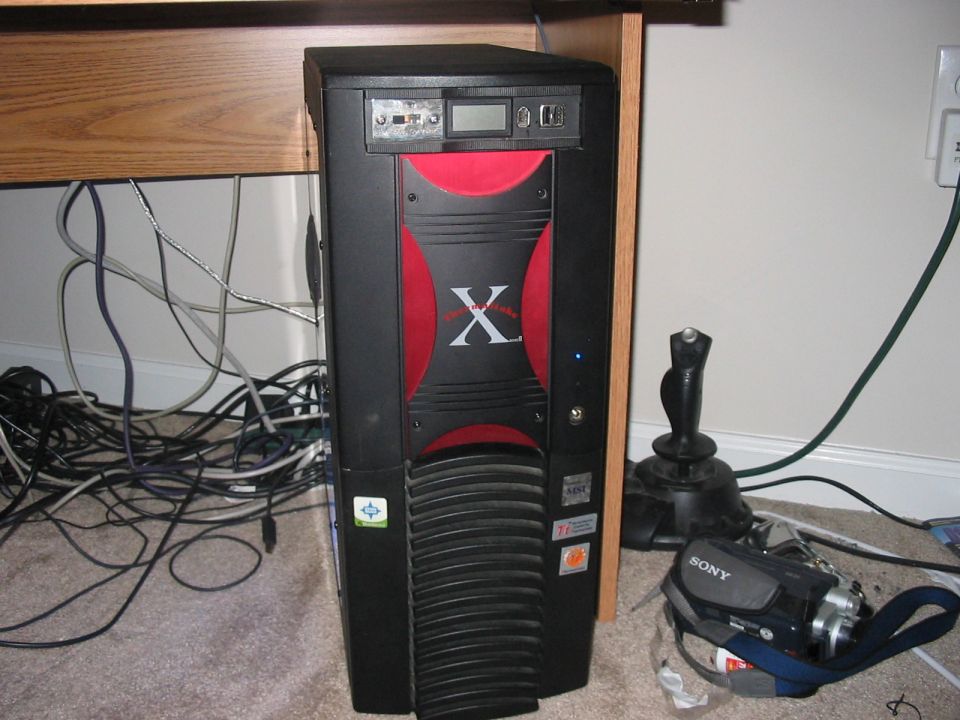Black computer tower with red accents, a joystick, and a Sony camcorder on the floor