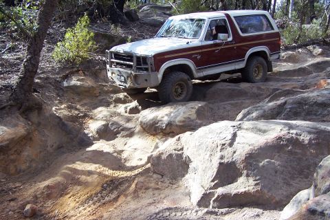 1982 Ford Bronco - A Ford Bronco is shown driving over large rocks on a trail.