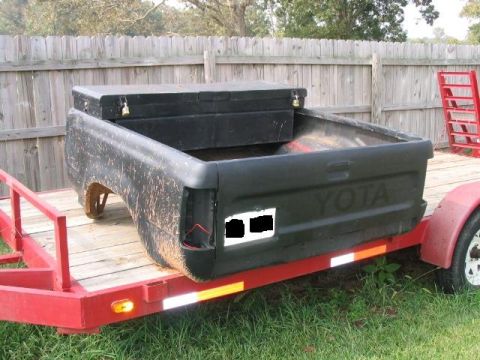 1986 Ford F-150 - A black truck bed, possibly from a Toyota, is loaded onto a red trailer.