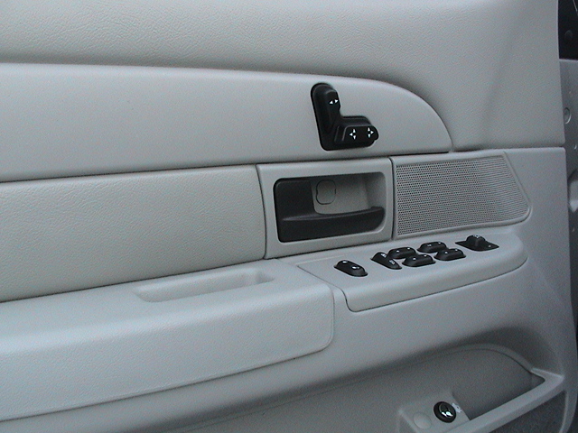 Light gray car interior door panel with power window and seat controls